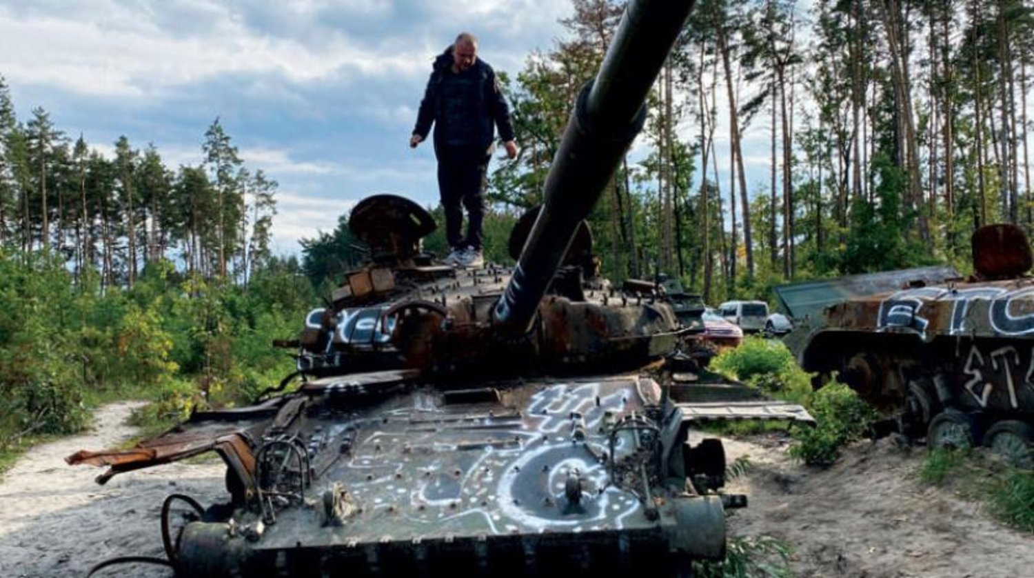 ایک شخص کل کیف کے قریب تباہ شدہ روسی ٹینک کے پاس سے گزر رہا ہے (اے پی)